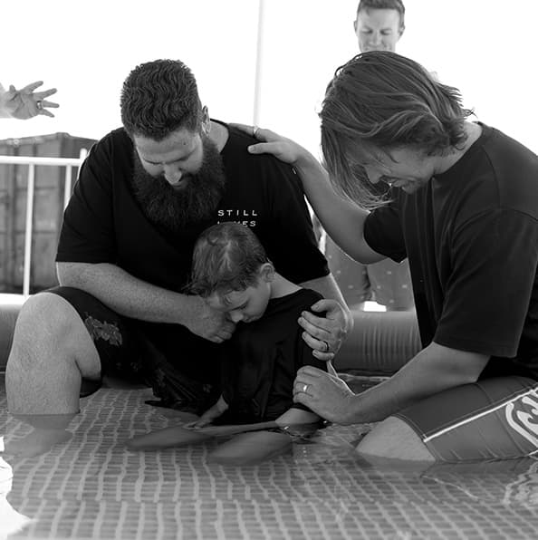 Child being baptised by church leaders in a baptism pool at City on a Hill Church