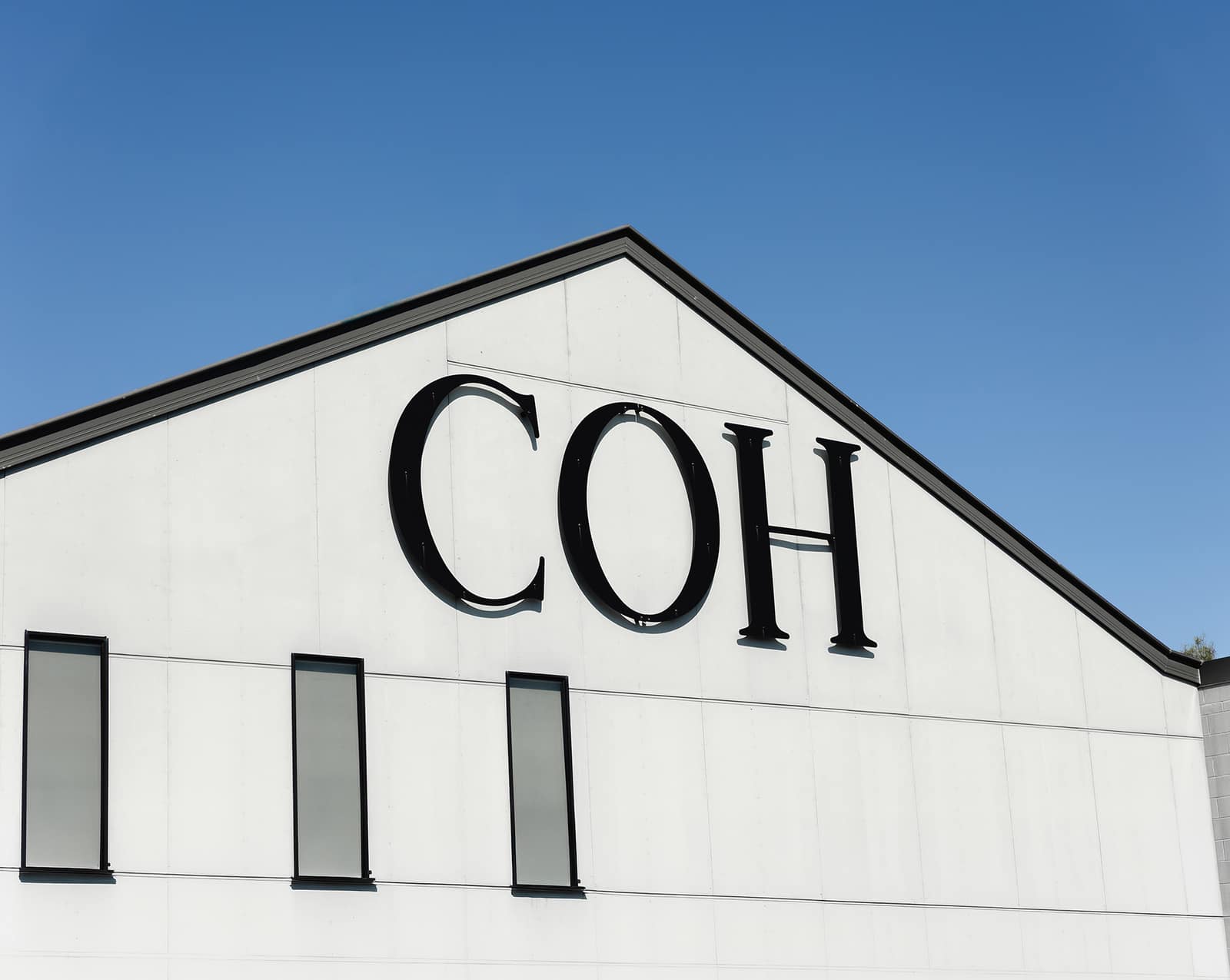 COH wordmark signage on the gable of the City on a Hill Church building against a blue sky